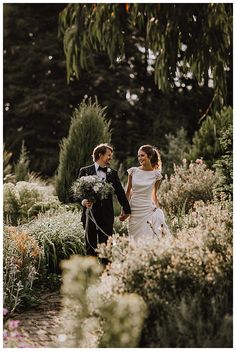 a bride and groom walking through the garden