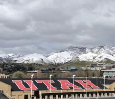 a stadium with mountains in the background and snow on the top half of its roof