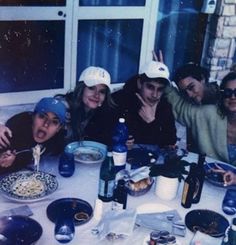 a group of people sitting around a table with food and drinks in front of them