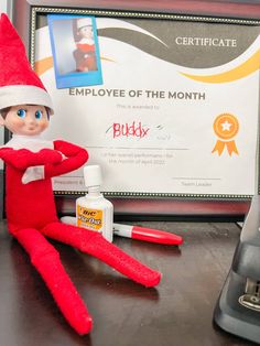 an elf is sitting on a desk next to a certificate