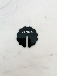 a white marble counter top with a black nameplate on it and the name jennya