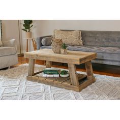 a living room with a couch, coffee table and rug on the floor in front of it