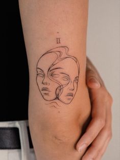 a woman's leg with a line drawing of two faces on the left side of her thigh