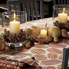 a table topped with a glass bowl filled with fruit and nuts next to a lit candle