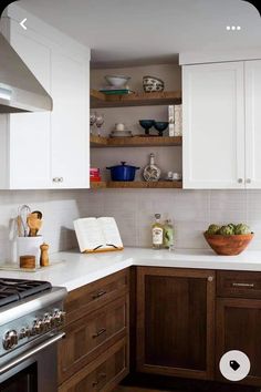 a kitchen with wooden cabinets and white counter tops, open bookshelves above the stove