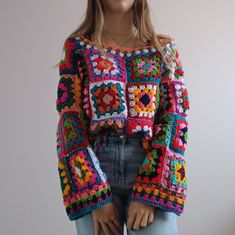 a mannequin wearing a colorful crochet sweater and jeans with her hands in her pockets