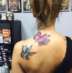 the back of a woman's neck with two butterflies on her upper and lower arm