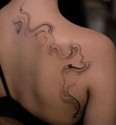 the back of a woman's shoulder with an abstract tattoo design on her left side