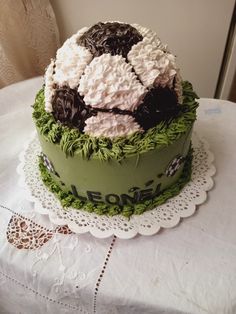 a green cake with white and black frosting sitting on top of a doily