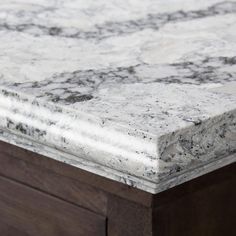 a marble counter top with dark wood drawers in the background and an open drawer on one side