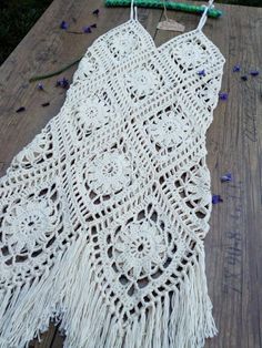 a crocheted doily is laying on a wooden table with beads and flowers