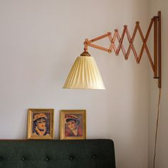 a lamp hanging from the side of a wall next to two pictures on a bed