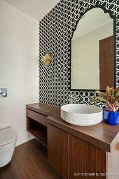 a bathroom with a sink, mirror and toilet in the background is decorated with black and white wallpaper