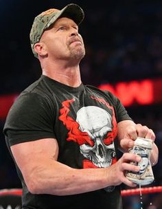 a man in a black shirt and hat holding a can with a skull on it