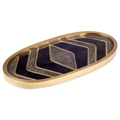 an oval shaped tray with gold trimming and black marble inlays on it