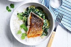 a white bowl filled with fish and rice on top of a blue and white table cloth