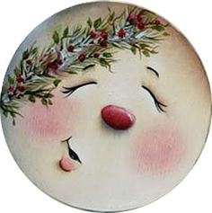 a ceramic plate with a face painted on it's side and leaves around its head