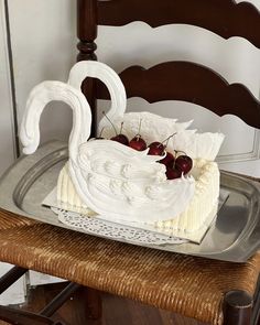 a cake with white frosting and cherries on it sitting on a metal platter