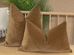 two brown pillows sitting on top of a bed next to a green palm tree in the background