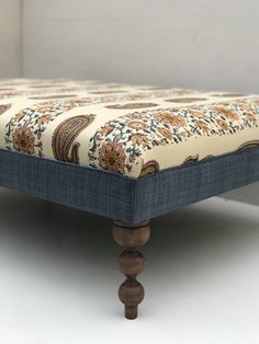 an upholstered foot rest made out of wood and fabric