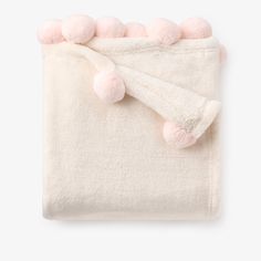 a white blanket with pink pom poms on it