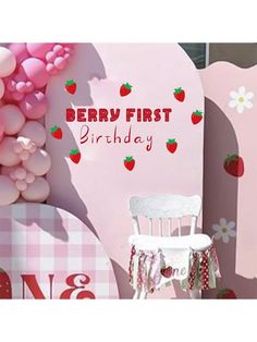 there is a pink birthday sign with strawberries on it and balloons in the background