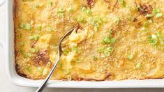 a casserole dish with green onions and cheese on top, ready to be eaten