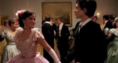 the young man and woman are dressed in period costumes, talking to each other as they dance