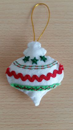 a white ornament with green and red trimmings on it sitting on a wooden surface