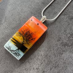 a glass pendant with a tree and birds in the sky on a gray carpeted floor