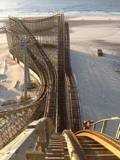 an aerial view of a roller coaster at the beach with snow on the ground and water in the background