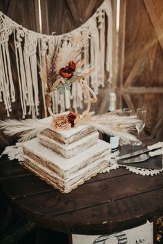 a cake sitting on top of a wooden table next to a white lace banner with feathers