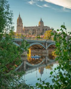 there is a boat on the water in front of a bridge and castle like building