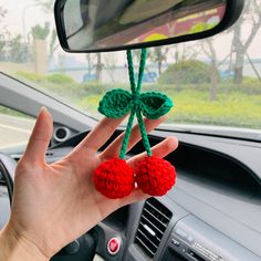 a hand holding two pom - poms in front of a car's rearview mirror