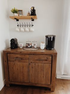 a wooden cabinet with coffee cups and other items sitting on it's top shelf