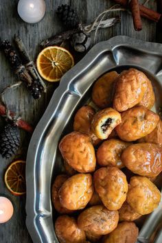 a metal bowl filled with pastries next to an orange slice and some cinnamon sticks