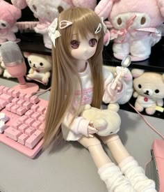 a doll sitting on top of a desk next to a keyboard and some stuffed animals