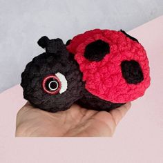 two black and red crocheted ladybugs sitting on top of each other