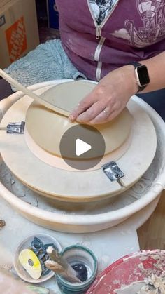 a woman is working on some pottery with her hands and making it look like she's doing something