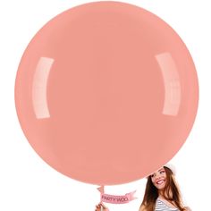 a woman holding a large pink balloon in front of her face