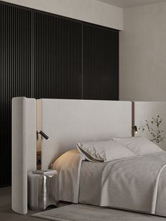 a bed with white sheets and pillows in a room next to a tall black wall