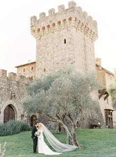 a bride and groom standing in front of a castle