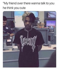 a man with dreadlocks standing in front of an office cubicle and looking at the camera