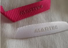 two white and pink hair ties with the name martin on them, one for women