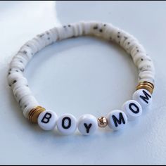 a white beaded bracelet with the word mom written in black and gold letters on it