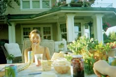 a woman sitting at a table with food and drinks in front of her, outside