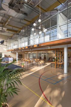 an indoor basketball court with several tables and chairs in the center, surrounded by large glass balconies