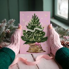 two hands holding up a card with a christmas tree on it