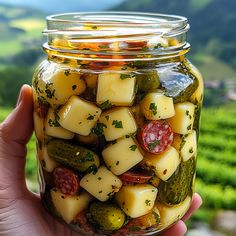 a jar filled with pickles and cheese on top of a green hillside in the background