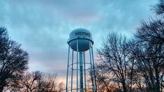 a tall water tower sitting in the middle of a park with trees on both sides